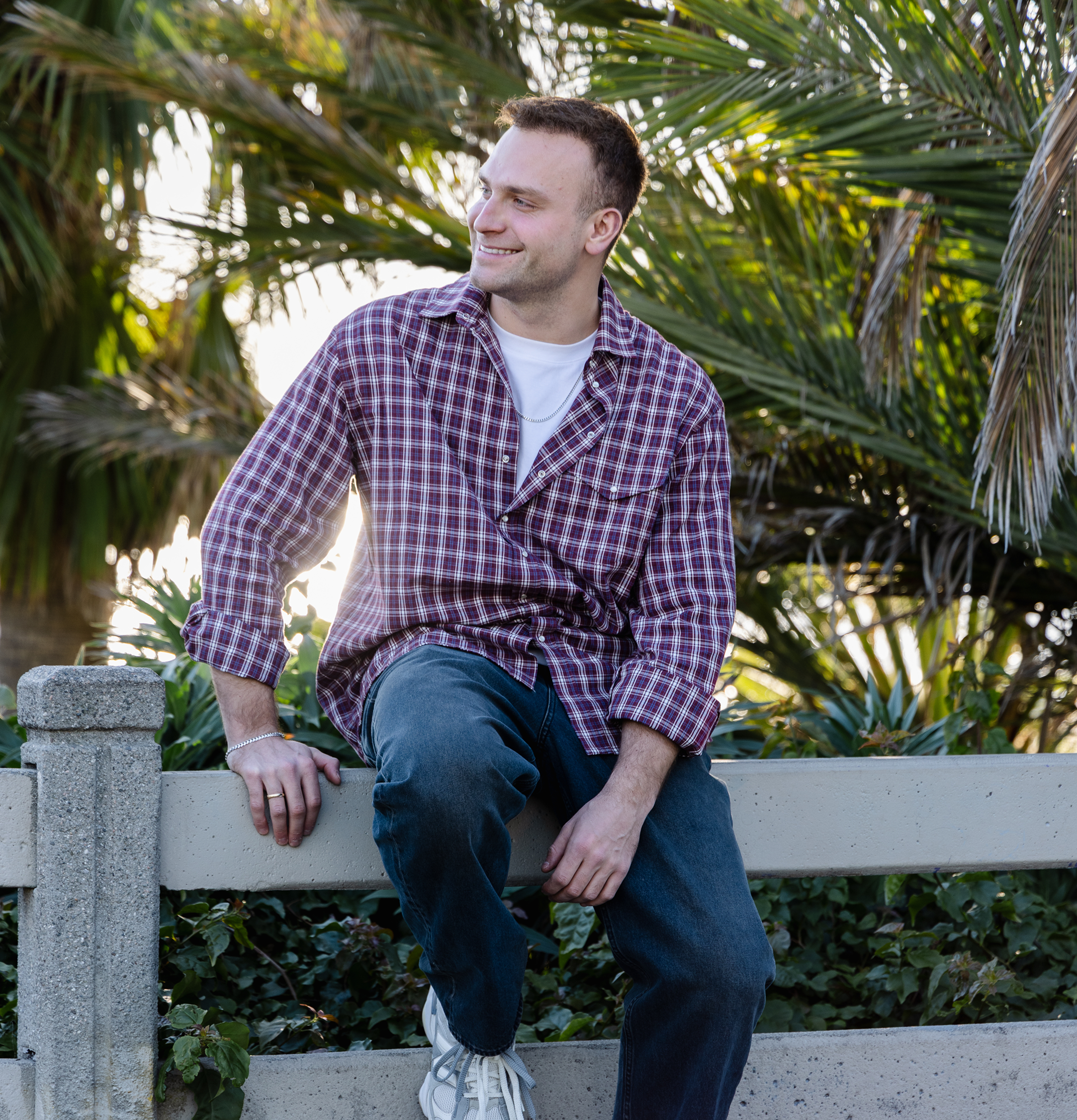 Man sitting on a bench with palm trees in the background